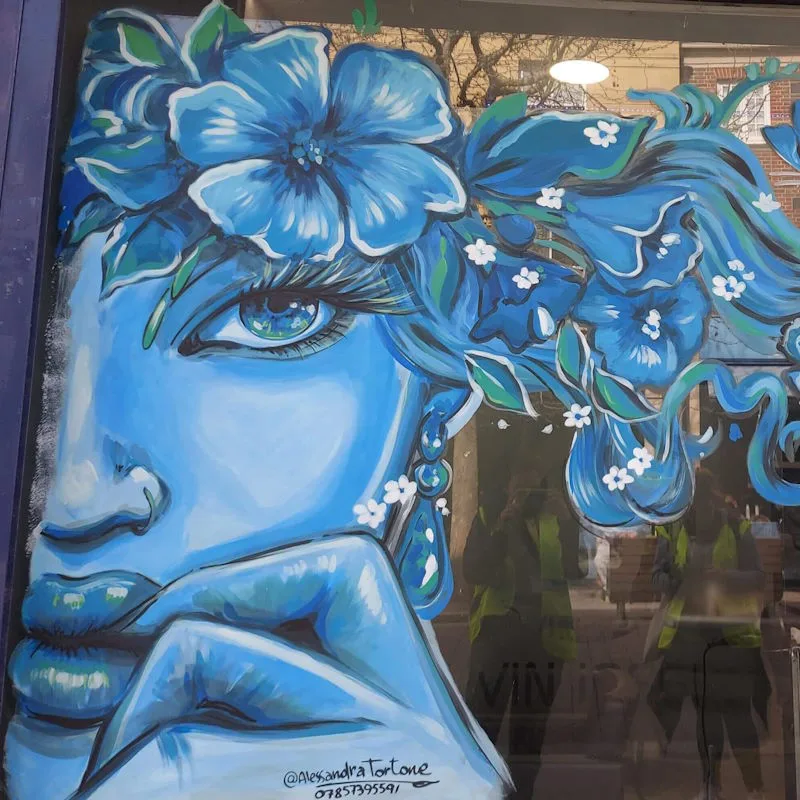 Hand painted window of the face of a lady with flowers in her hair, pained in a blue hue.